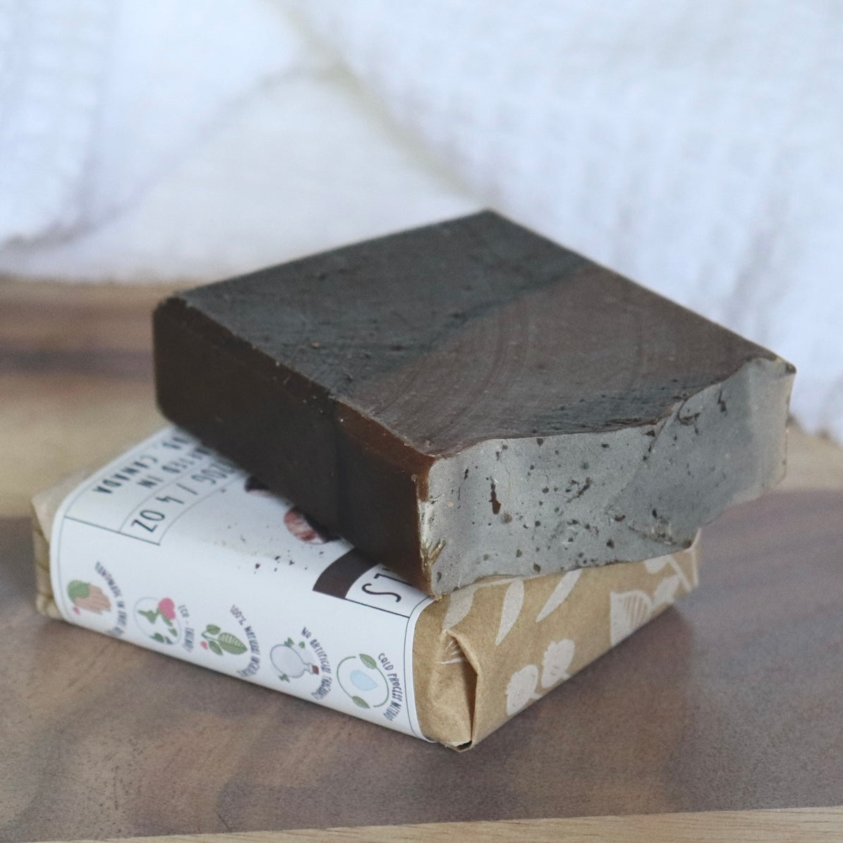 Bar of soap with a paper wrapper on a wooden surface