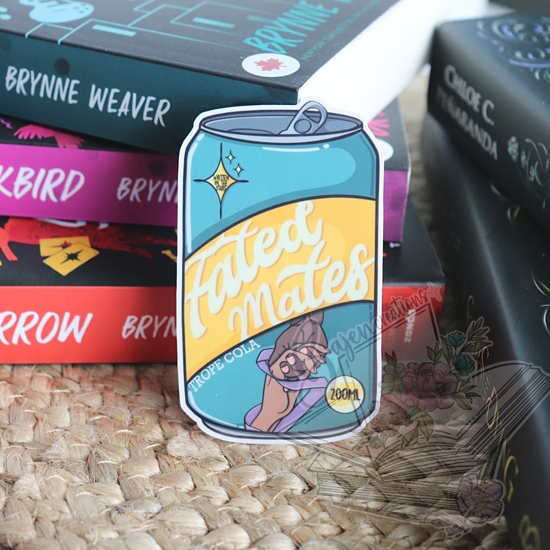 Sticker of a can labeled 'Fated Mates' on a textured surface with book spines in the background.