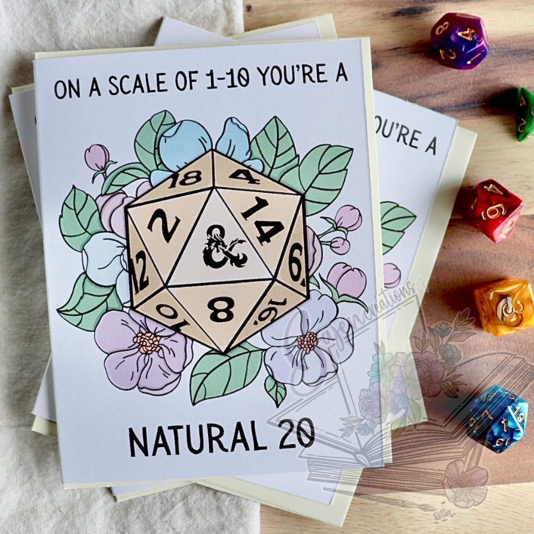 Greeting card with a D20 die surrounded by flowers on a wooden surface with dice.