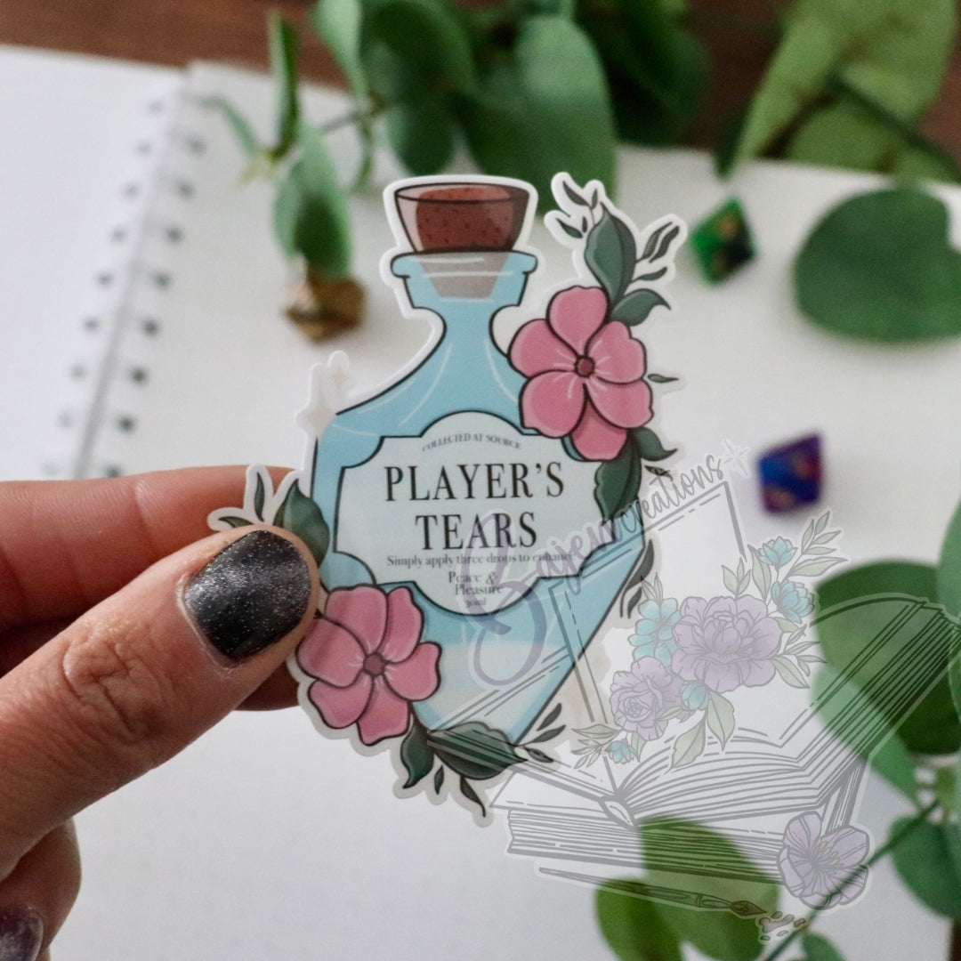 Sticker of a bottle labeled 'Player's Tears' held by a hand with a blurred background