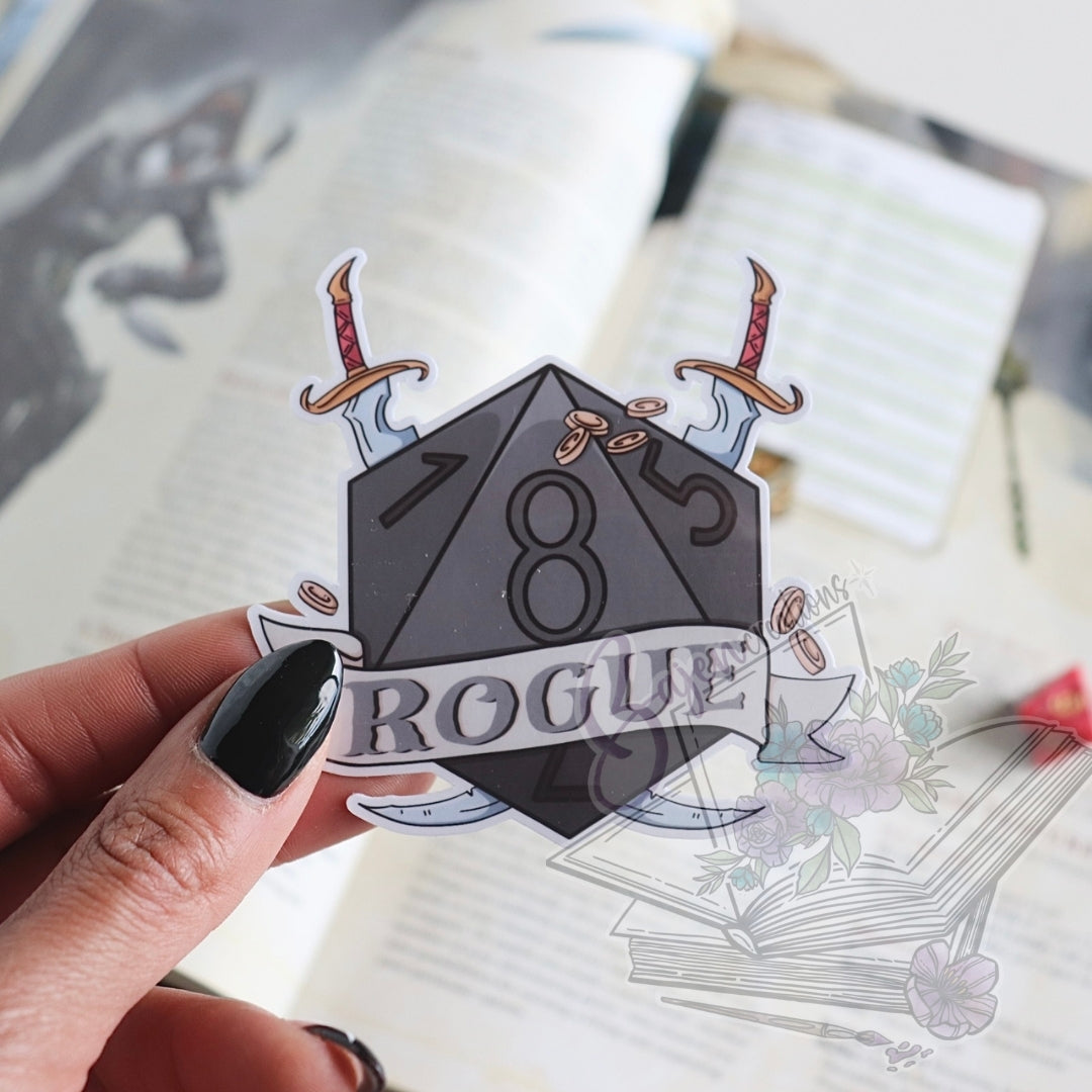 Sticker with a dice design and 'Rogue' text held by a hand on a blurred background