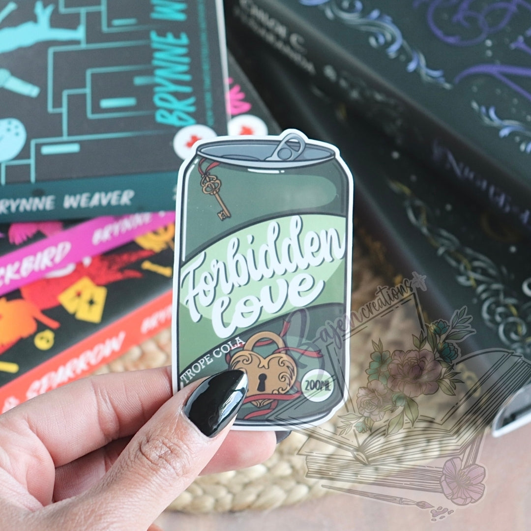 Sticker of a can labeled 'Forbidden Love' held by a hand with black nail polish, with books in the background.